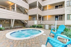 A pool area with a hot tub, lounge chairs, and a staircase leading to upper floors. - Oceanfront Condo with Screened Oceanfront Balcony + Free Attraction Tickets! (North Myrtle Beach)