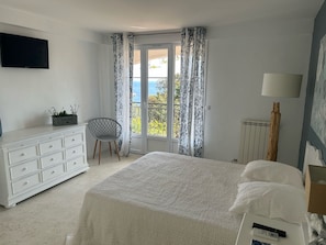 Ett sovrum med en säng, en byrå, en stol, en lampa och en tv.