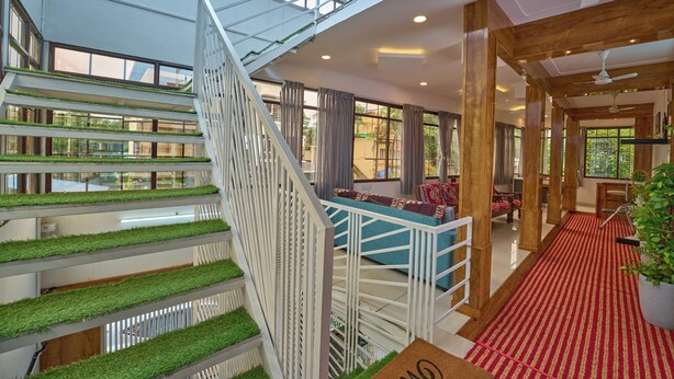 A multi-level interior with a central staircase, glass railings, and a red carpeted area. - Panakal Residency (Kochi)