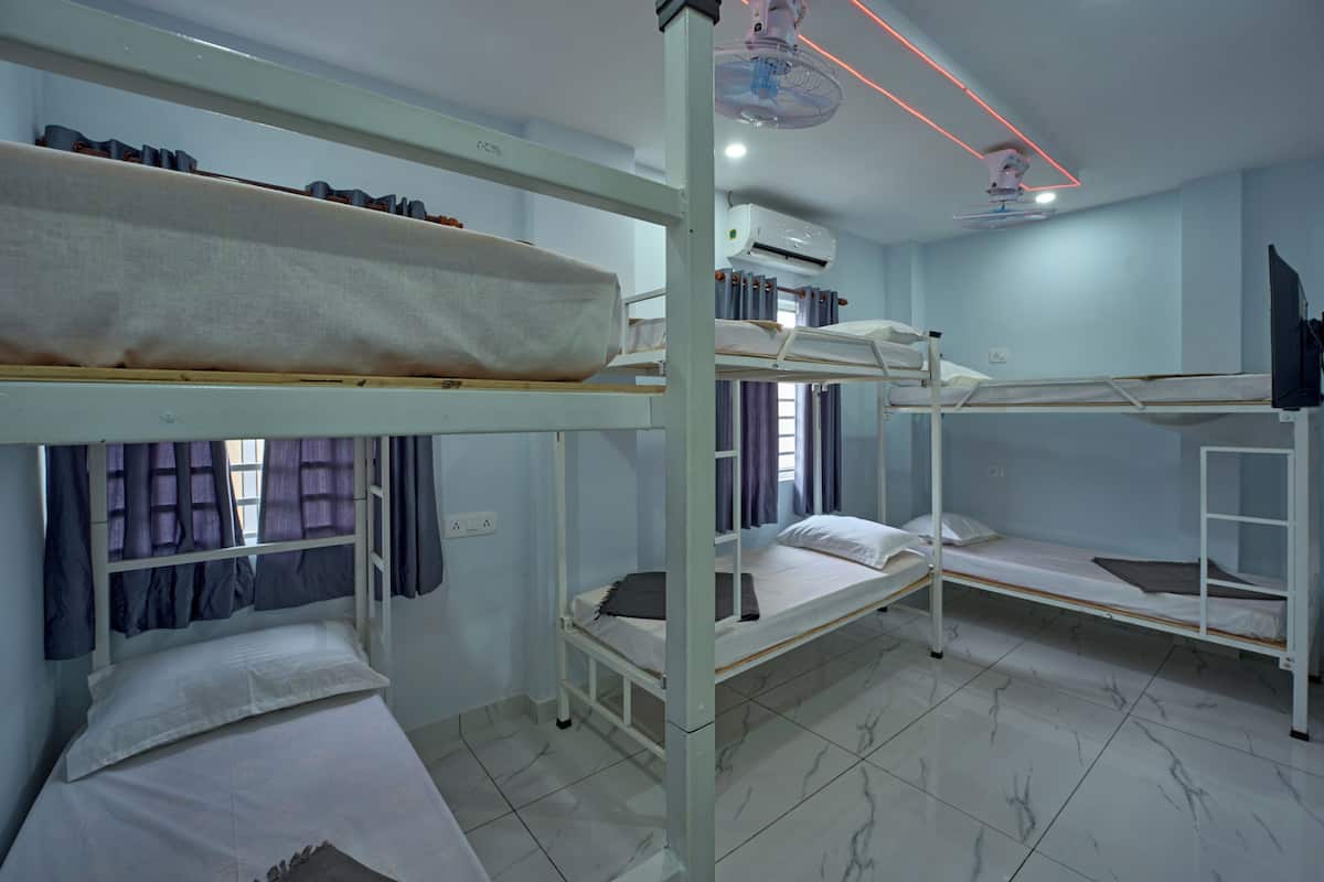 A dormitory room with bunk beds, a ceiling fan, and an air conditioning unit.