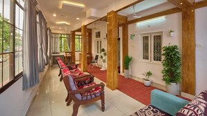A hotel lobby with wooden pillars, a red carpet, and seating areas. - Panakal Residency (Kochi)