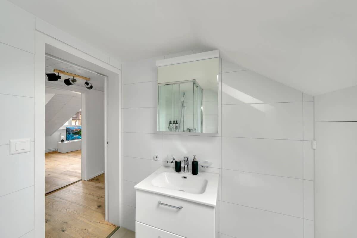 Un baño moderno con lavamanos, espejo y mueble de almacenamiento blanco.
