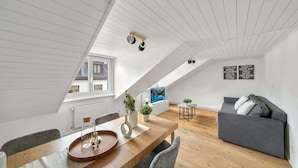 Um apartamento loft moderno com área de refeições, um sofá cinza e televisão na sala de estar.