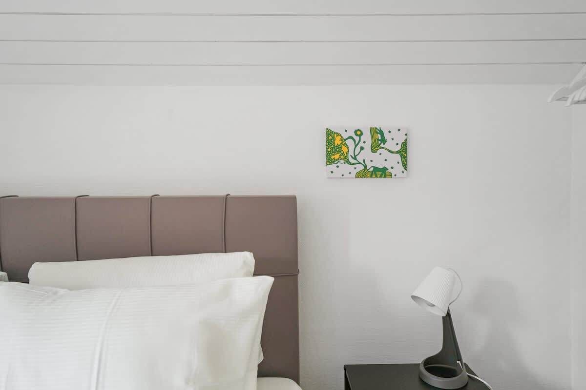 Un dormitorio con una cama, una mesita de noche y una lámpara de pared.