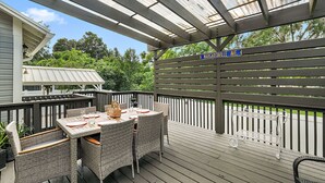 An outdoor deck with a covered patio area, a table set for dining, and a sign indicating the name of the street. - "The Hanscom House" 8 MIN walk to DT! (Mount Dora)