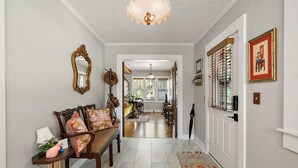 A hallway with a wooden bench, a mirror, and a chandelier. - "The Hanscom House" 8 MIN walk to DT! (Mount Dora)