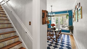 A staircase with patterned steps leading to a dining area with a checkered floor, a table, chairs, and a hanging plant. - "The Hanscom House" 8 MIN walk to DT! (Mount Dora)