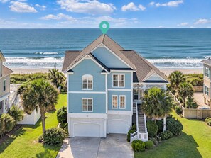 A two-story house with a garage, located near a beach with ocean views.