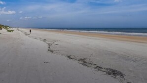 Una extensa playa de arena con cielo despejado y algunas nubes.