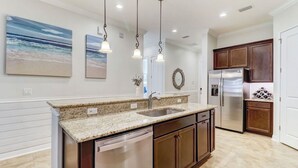 Una cocina moderna con encimeras de granito, electrodomésticos de acero inoxidable y armarios de madera.