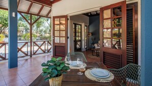 Un espace extérieur abrité, aménagé pour les repas, avec une table en bois pour deux personnes, entourée de chaises.