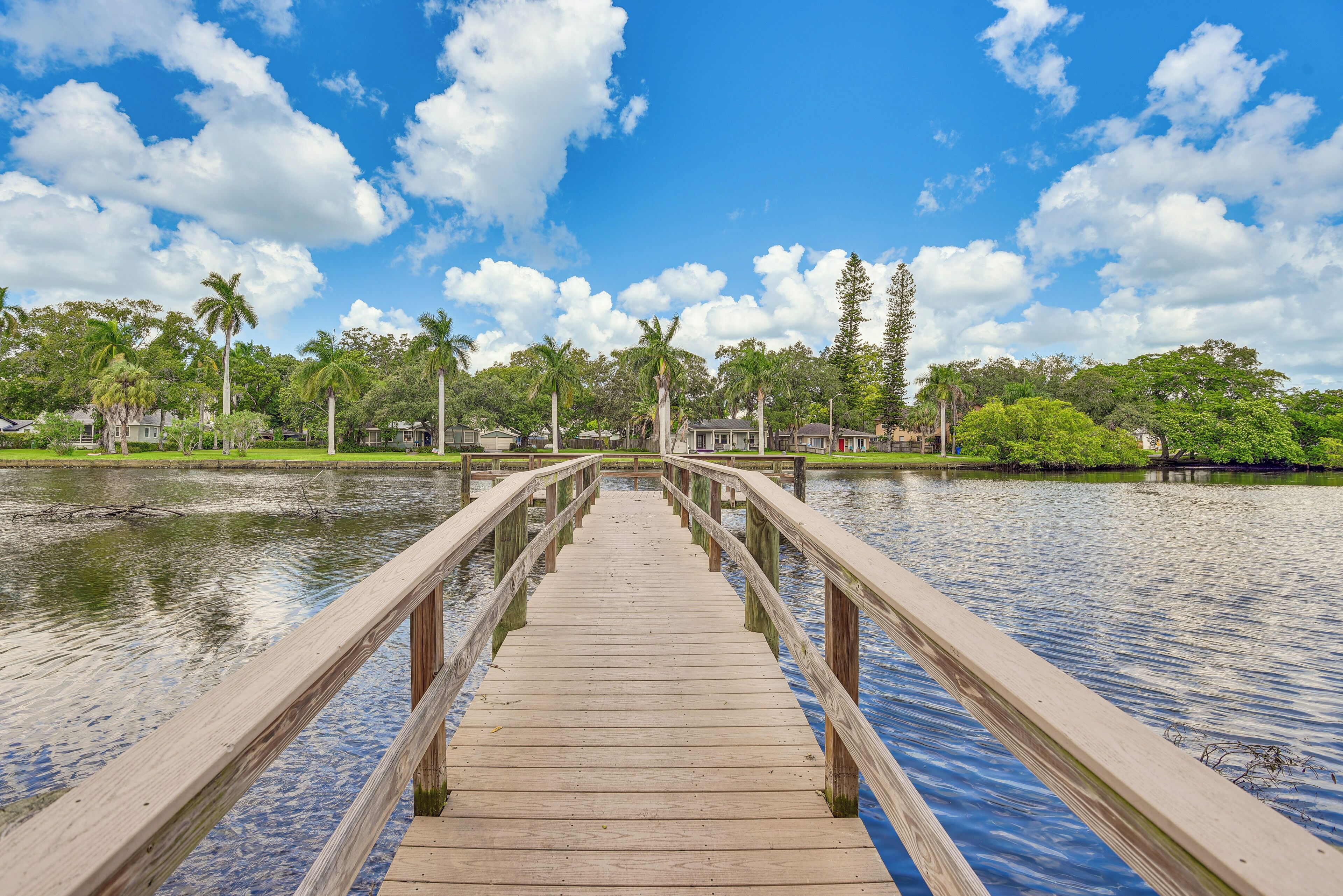 Un puente de madera que conduce a un edificio con vistas al agua y palmeras.