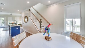 A spacious living room with a round white table, a colorful bird sculpture, and a staircase leading to another level. - 1 Mi to Riverwalk: Brand New Bradenton Home (Bradenton)