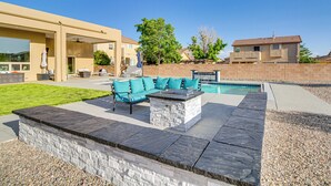 Eine moderne Terrassenanlage mit einem Steinkamin, einem blauen Sofa und einem Pool.