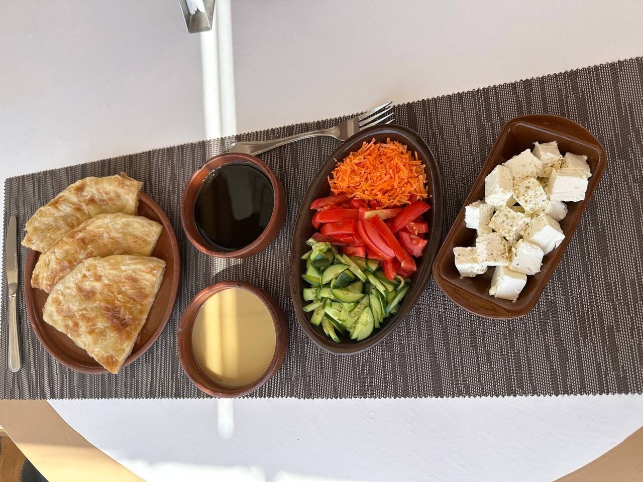 A meal with three types of food and two sauces on a table.