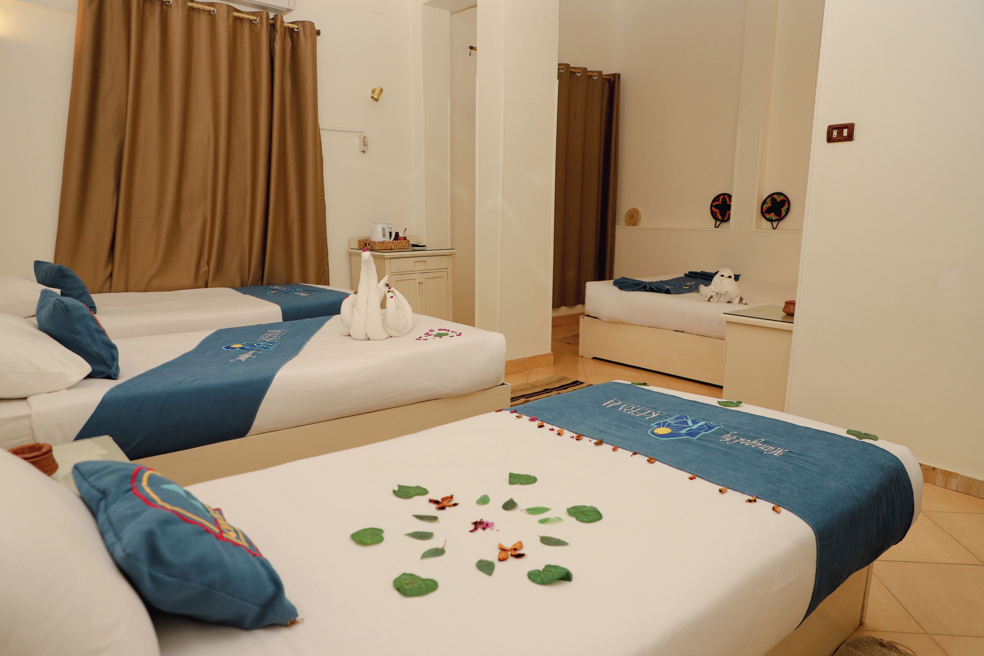 Une chambre d’hôtel avec deux lits, une petite table, un miroir et une fenêtre avec des rideaux.