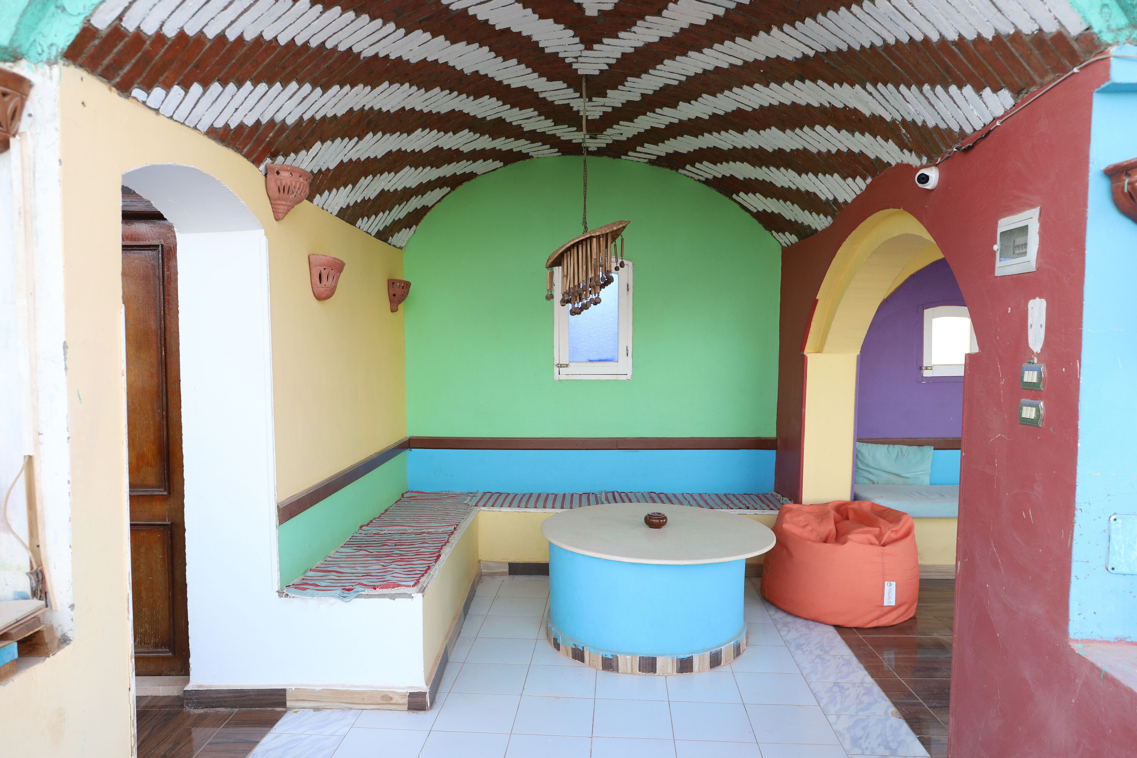 Une pièce avec un banc, une table ronde et un plafond aux couleurs vives.