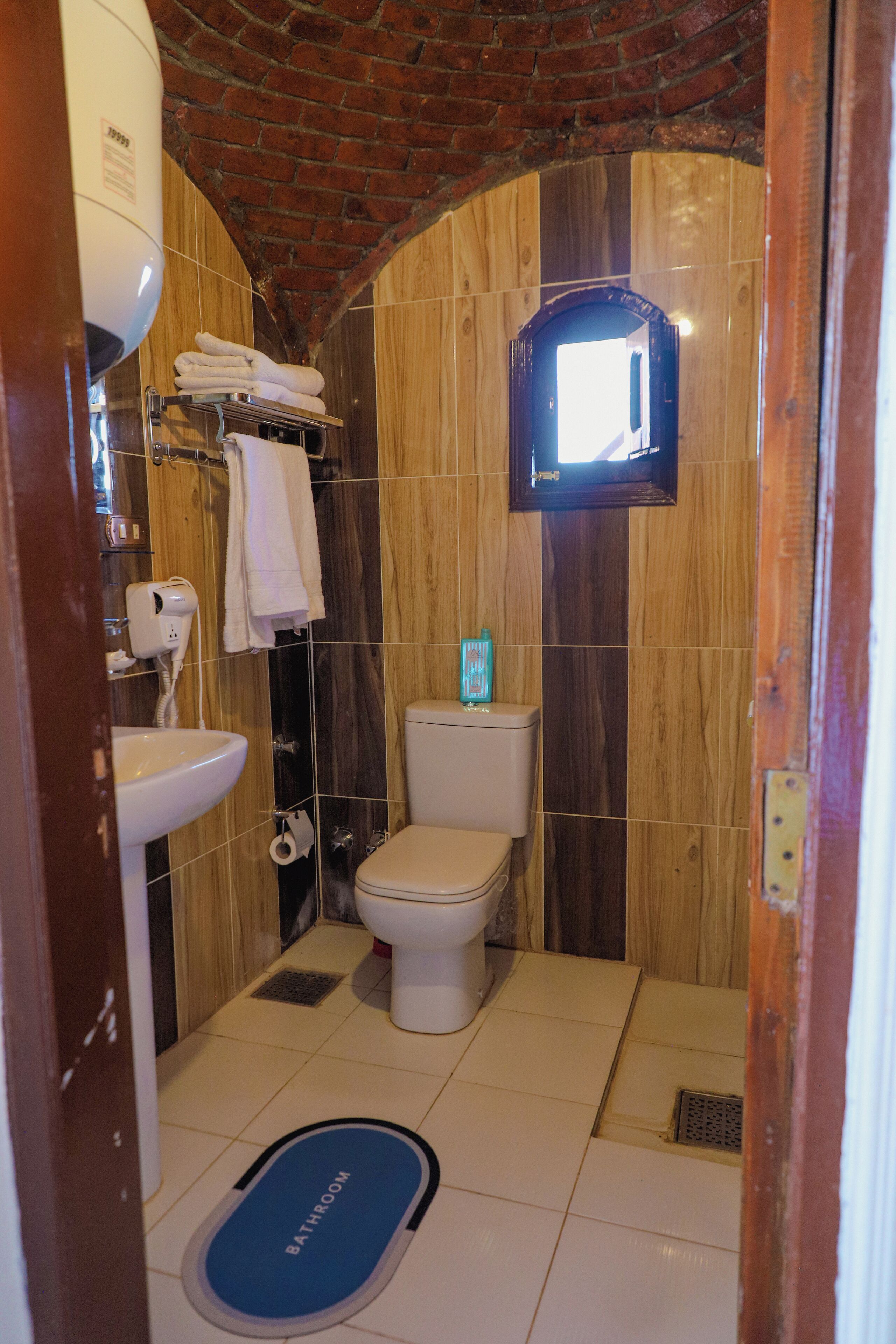 Une salle de bain avec un mur en bois, un lavabo, des toilettes et un tapis bleu sur lequel est écrit « salle de bain ».