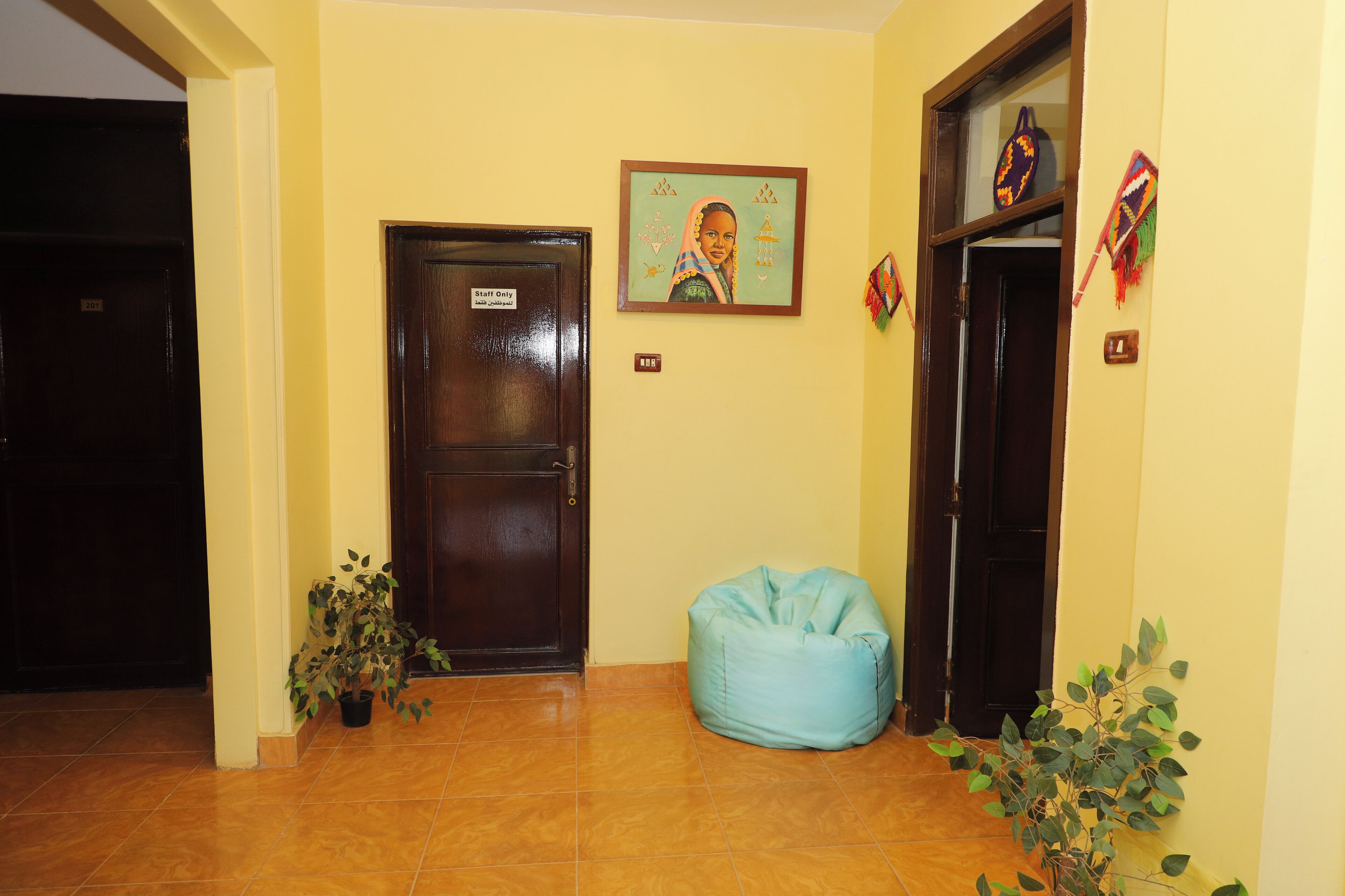 A hallway with a closed door labeled "Staff Only," a blue bean bag chair, and a potted plant.