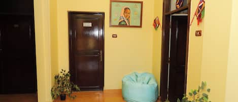 Um corredor com uma porta fechada com a inscrição 'Somente para Funcionários', uma poltrona de tecido azul e um vaso de plantas.