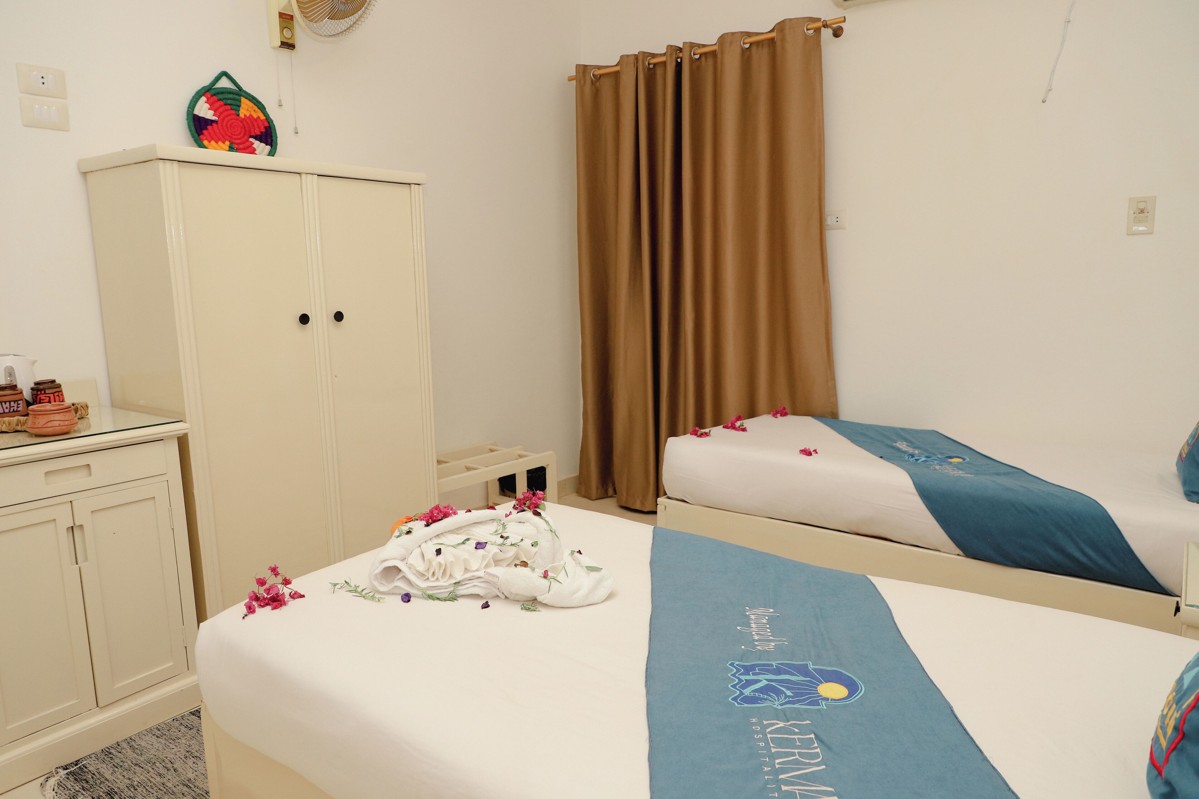 Ein Hotelzimmer mit zwei Betten, einem Kleiderschrank und einem dekorativen Gegenstand an der Wand.