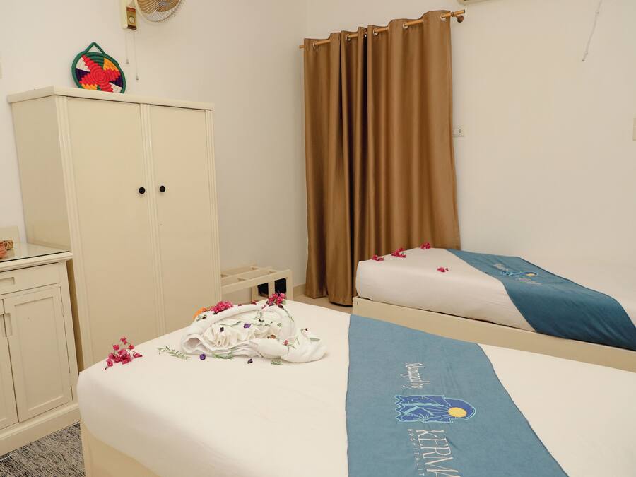Una habitación de hotel con dos camas, un armario y un objeto decorativo en la pared.