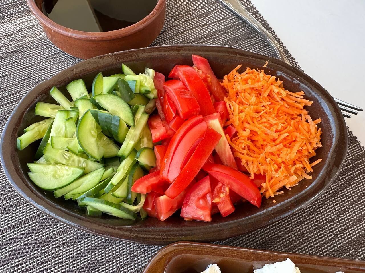 Un plato con rodajas de pepino, tomates y zanahoria rallada.