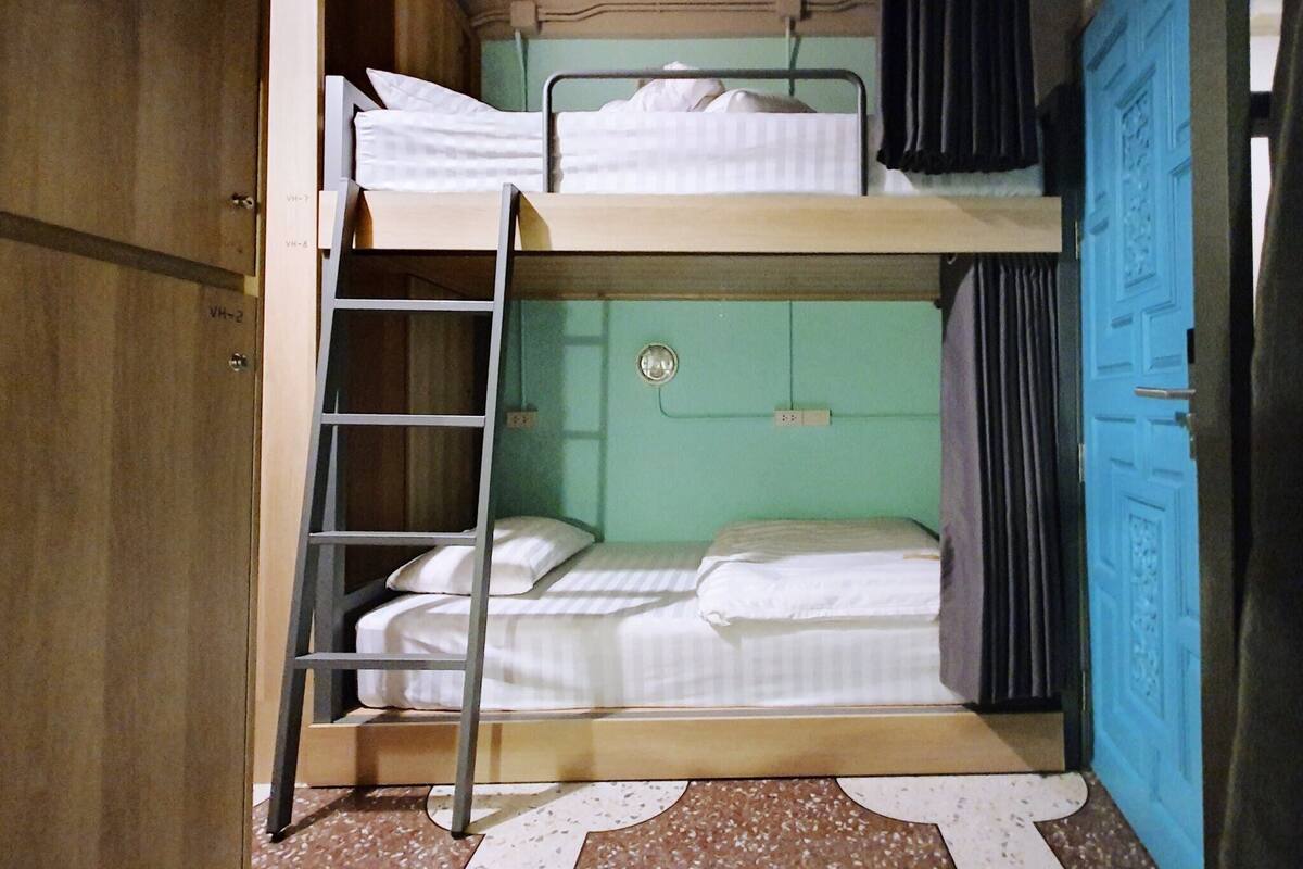 A bunk bed room with a ladder, a blue door, and a wardrobe.