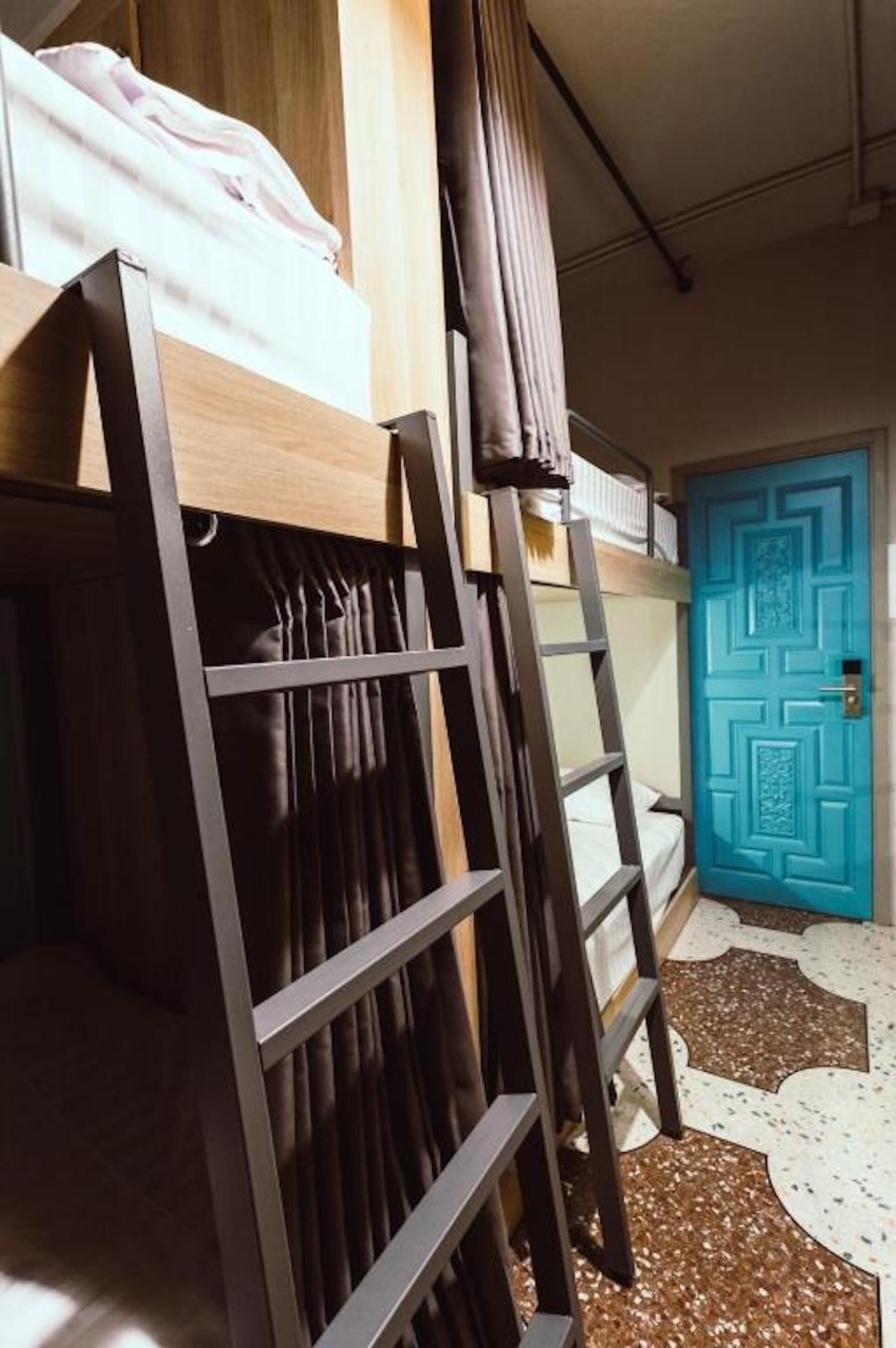 A bunk bed with a ladder, a blue door, and a patterned rug.