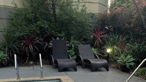 A circular hot tub with a tiled edge, surrounded by lounge chairs and plants. - Jolimont Views - Centrally located top floor apt overlooking MCG/Rod Laver (East Melbourne)