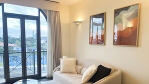 A modern living room with a glass coffee table, a beige sofa, and two abstract paintings on the wall. - Jolimont Views - Centrally located top floor apt overlooking MCG/Rod Laver (East Melbourne)