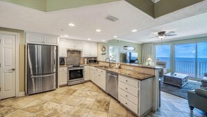 A spacious kitchen with a large island, stainless steel appliances, and a view to the outside. - Treasure Island 804- Heated Pool, Hot Tub, Grills, FREE Golf & Beach Service! (Panama City Beach)