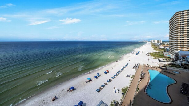 A beachfront hotel with a pool, beach chairs, umbrellas, and a view of the ocean. - Treasure Island 804- Heated Pool, Hot Tub, Grills, FREE Golf & Beach Service! (Panama City Beach)