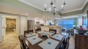 A spacious kitchen with a dining area, a chandelier, and a view of the ocean. - Treasure Island 804- Heated Pool, Hot Tub, Grills, FREE Golf & Beach Service! (Panama City Beach)
