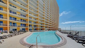 A hotel with a large pool, multiple balconies, and sun loungers. - Pet Friendly Treasure Island 1504- Heated Pool, Gym, FREE Golf &Beach Service (Panama City Beach)