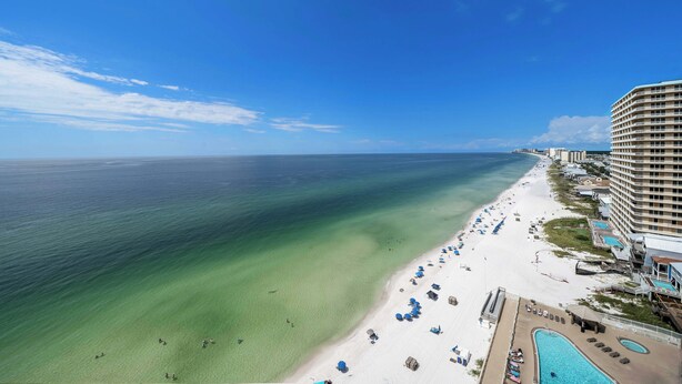 A beachfront hotel with a pool, beach umbrellas, and a clear view of the ocean. - Pet Friendly Treasure Island 1504- Heated Pool, Gym, FREE Golf &Beach Service (Panama City Beach)