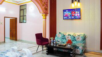 A hotel lobby with a reception desk, a sofa, a chair, and a TV mounted on the wall.