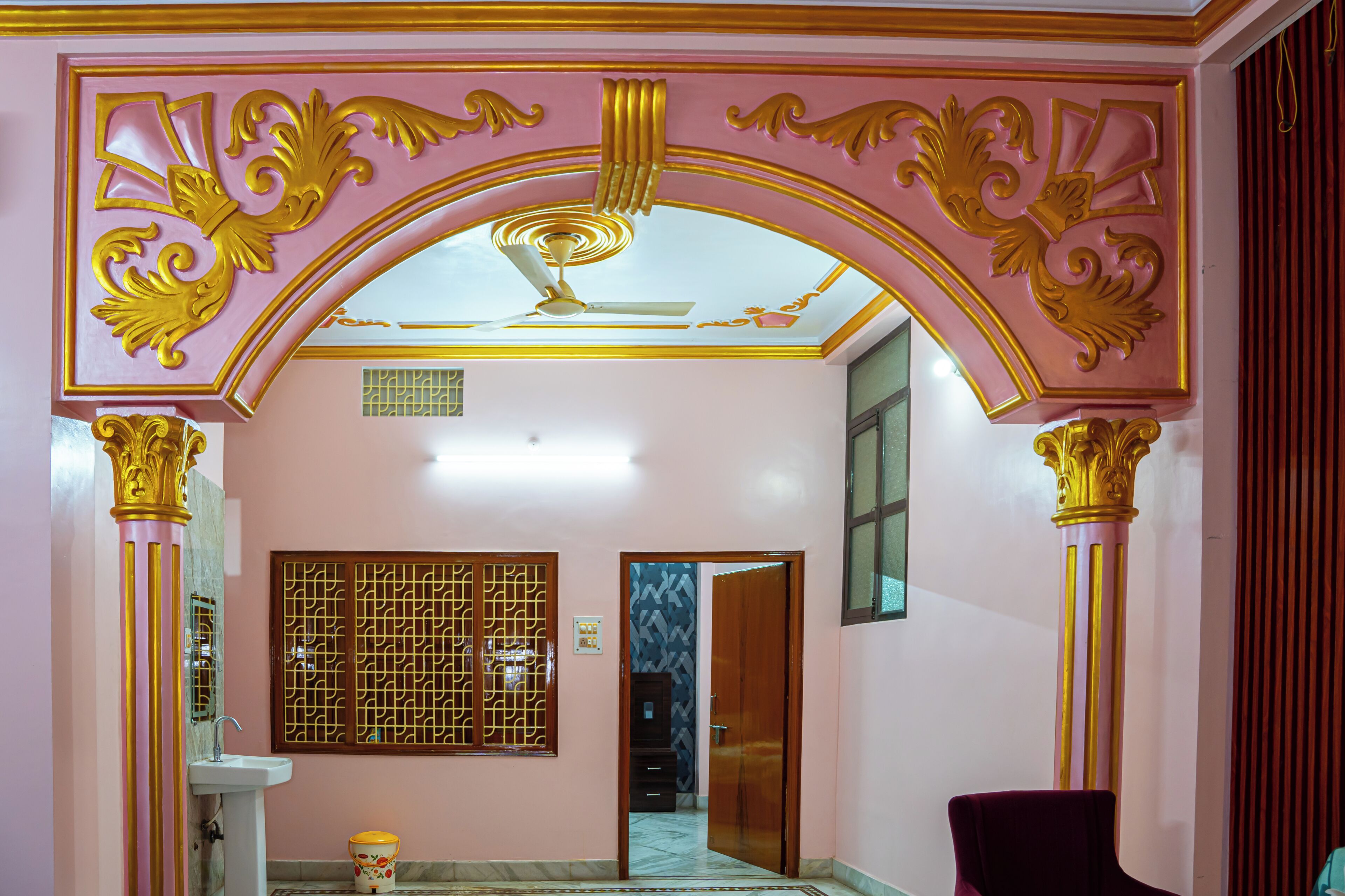An interior hallway with a decorative archway, a ceiling fan, and a door leading to another room.