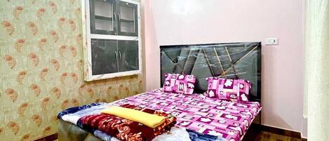Un dormitorio con cama, ventilador de techo, ventana y papel tapiz estampado.