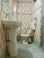 A bathroom with a pedestal sink, toilet, and shower.