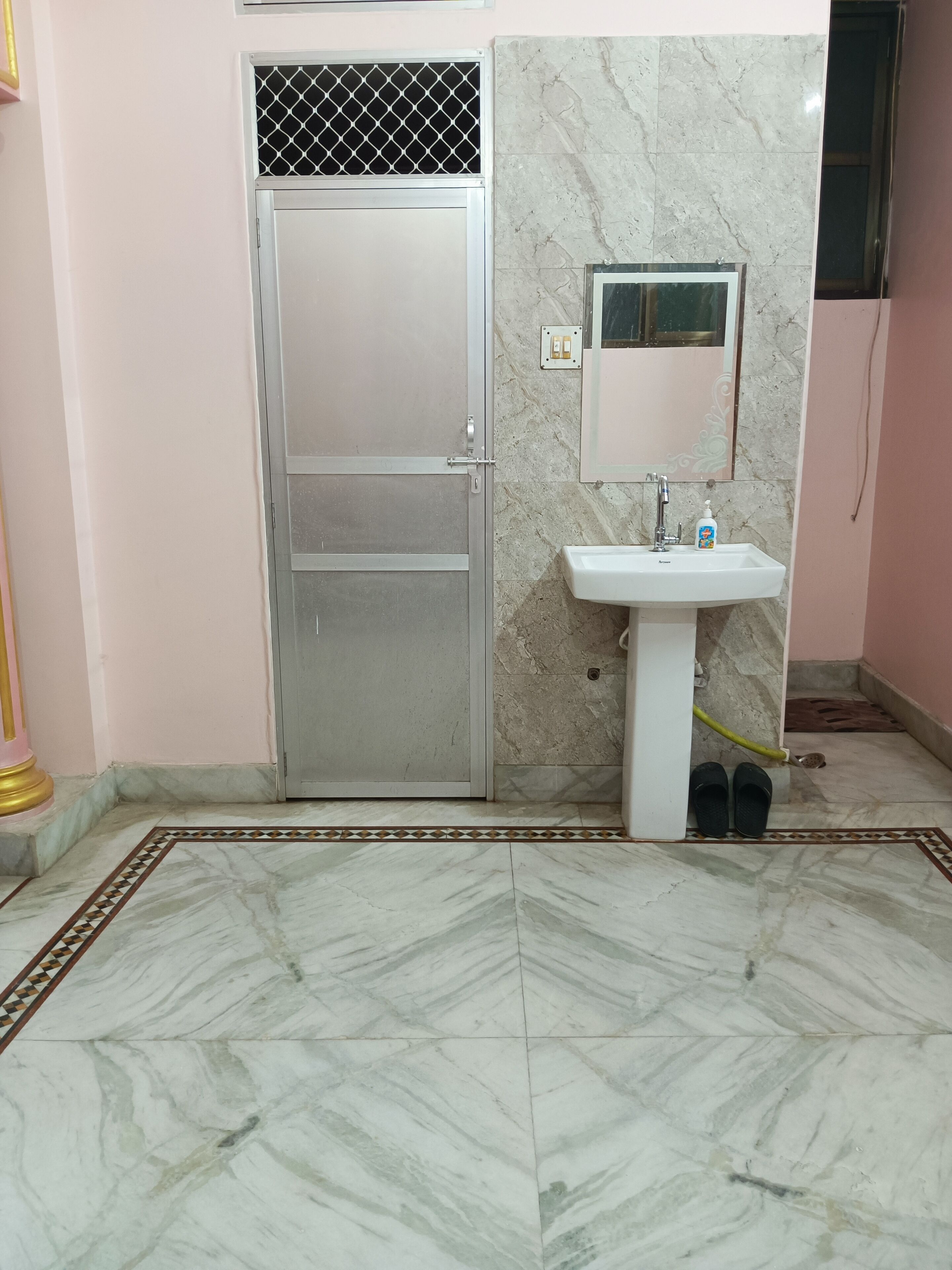 A bathroom with a marble floor, a white sink, and a closed door.
