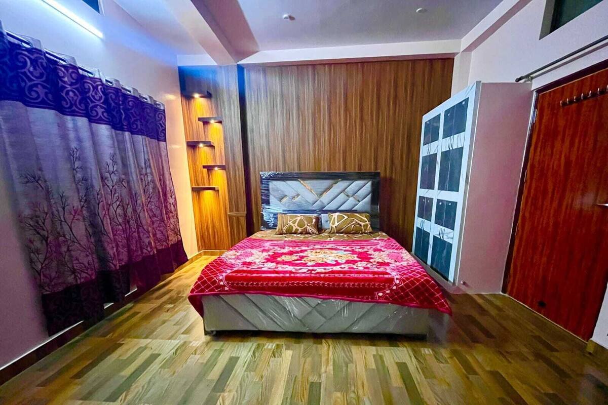 A bedroom with a bed, wooden flooring, a headboard, and a window.