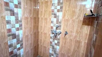 A shower with a checkered tile pattern, a red bucket, and a metal shelf.