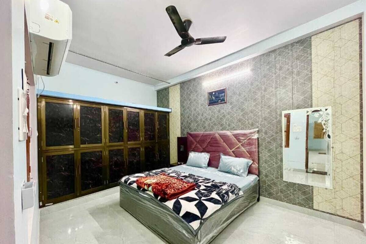 A bedroom with a bed, a ceiling fan, a wardrobe, and a mirror.