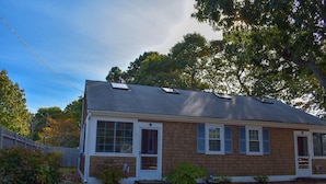 A single-story house with a sloped roof, a front porch, and a small front yard with gravel and shrubs.