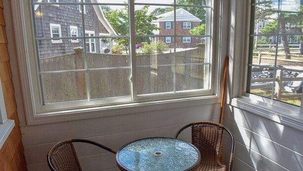 A sunroom with a large window, two wicker chairs, and a small round table.