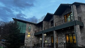 Een stenen gebouw met een balkon, een trap en een bord dat het een hotel identificeert.