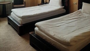 Een hotelkamer met twee bedden, een stoel, een klein tafeltje en een lamp.