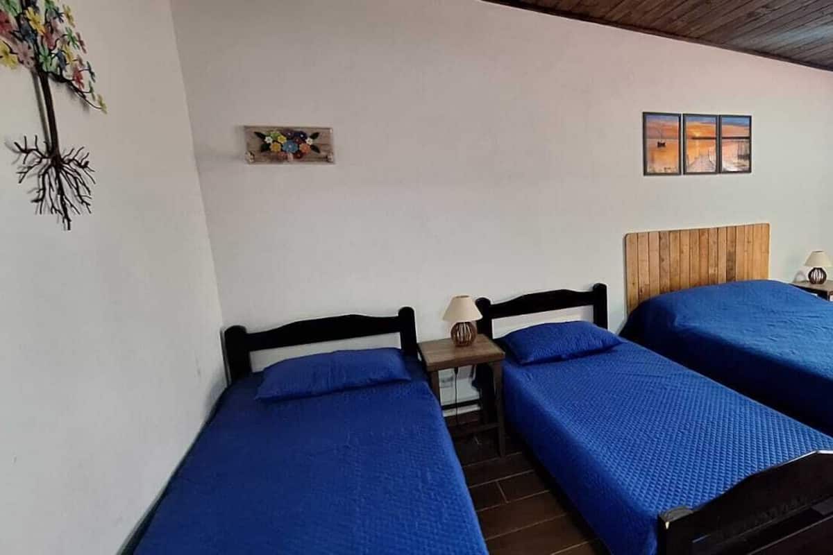 Een kamer met twee bedden, een bureau, een stoel, een lamp en een raam met gordijnen.