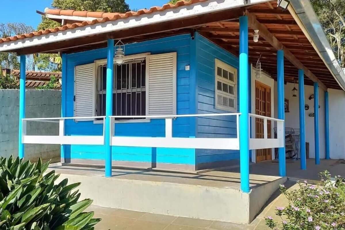 Een blauw huis met een veranda, een raam met luiken en een deur.